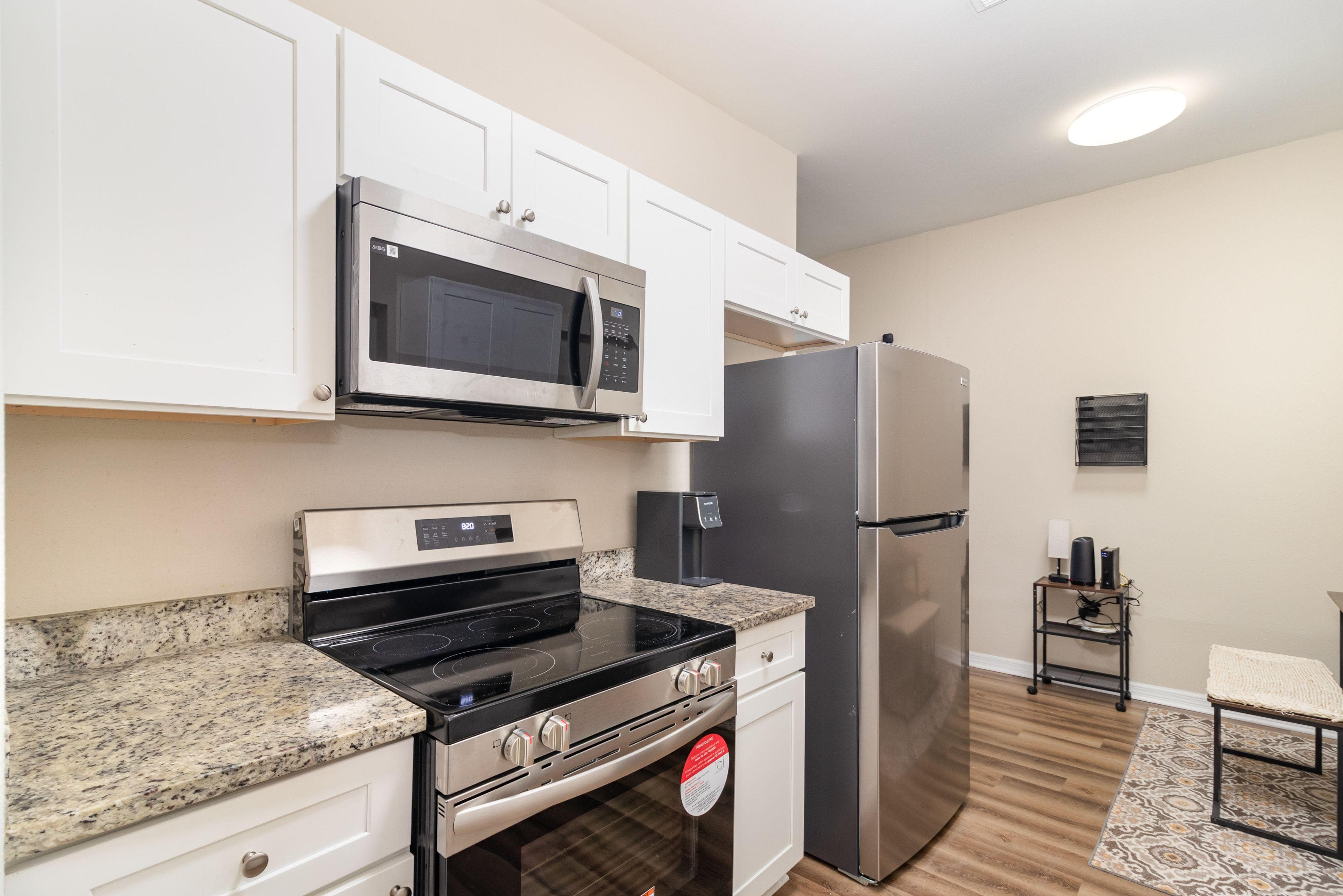 This stunning kitchen features modern stainless steel appliances, including a sleek refrigerator and an efficient range. The beautiful granite countertops provide ample space for meal preparation, while the cabinetry offers plenty of storage. Perfect for cooking up delicious meals just steps away from your room!