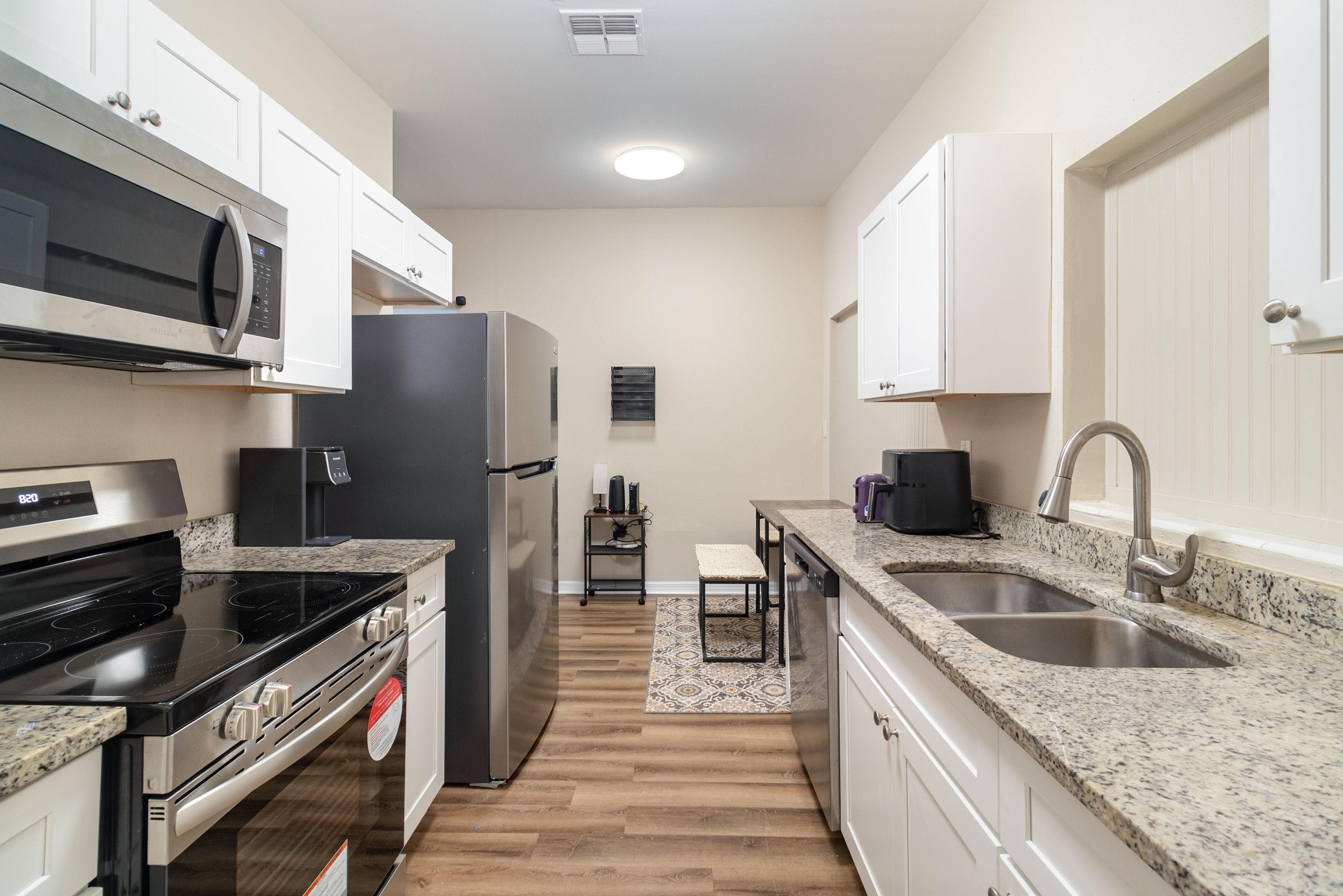 This modern kitchen boasts sleek stainless steel appliances and granite countertops, offering a stylish and functional space for cooking and socializing. The well-lit area ensures a warm ambiance, perfect for culinary adventures or quick meals.