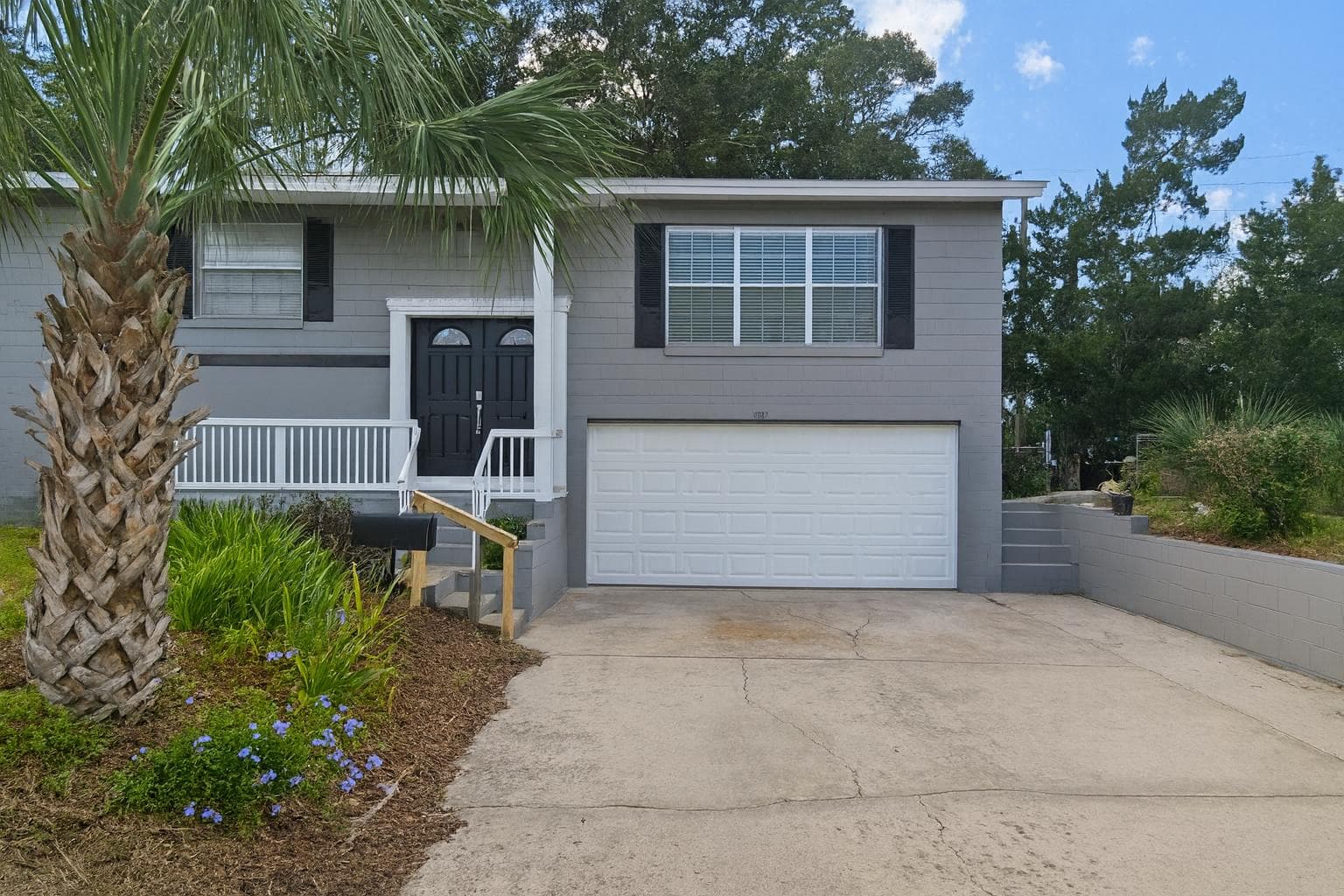 Discover your new home with this charming exterior view, showcasing a well-maintained property surrounded by lush greenery. The inviting entrance and spacious driveway create a warm welcome, perfect for a community-focused coliving experience.