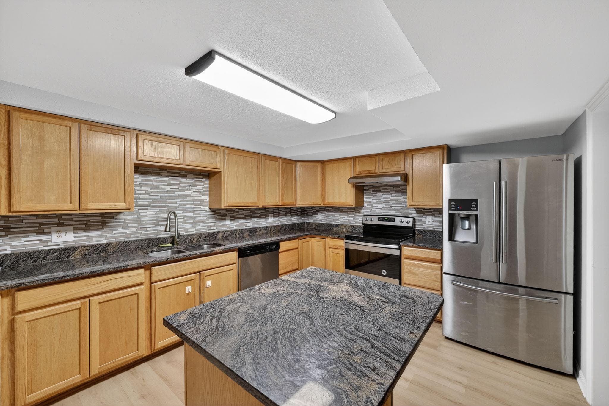 Step into this modern kitchen, featuring sleek granite countertops and ample cabinetry, perfect for culinary enthusiasts. The open layout invites you to prepare meals with ease, while the contemporary design ensures a stylish and inviting atmosphere for hosting friends and enjoying home-cooked dinners.