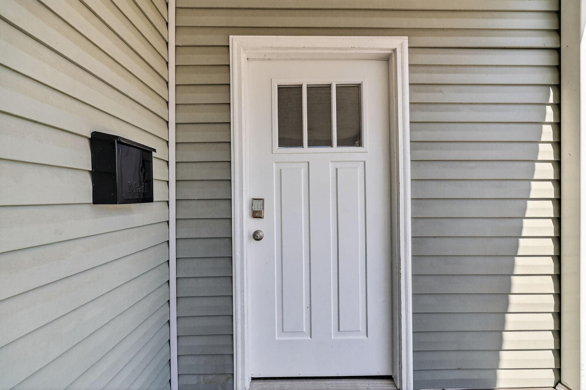 Welcome to your new home! This exterior shot showcases the inviting entrance of the property, featuring a clean, well-maintained front door that opens up to a vibrant coliving community. The subtle details in the siding hint at a cozy and comfortable living environment.