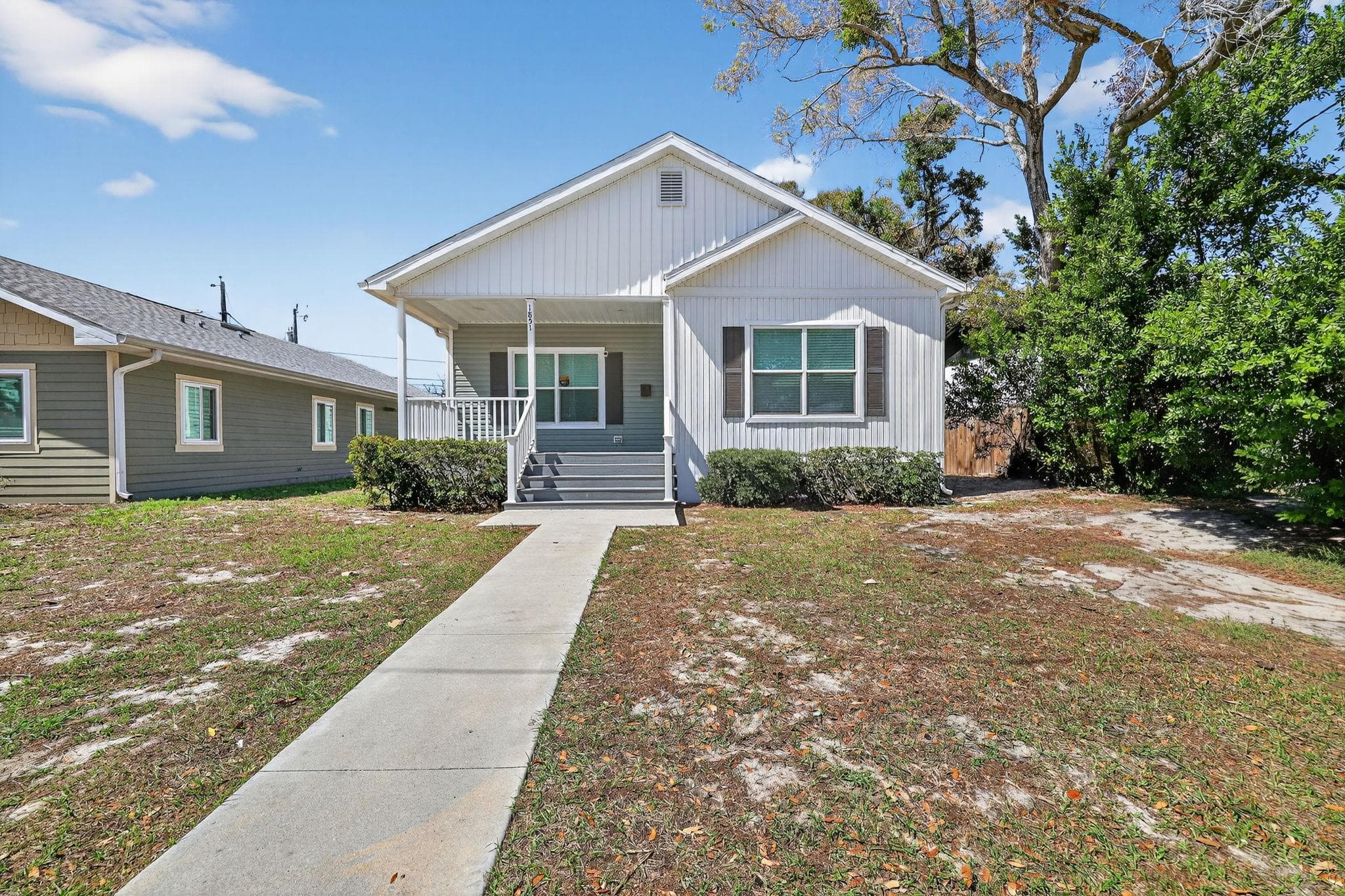 Welcome to your future home! This charming exterior features a welcoming entrance and well-kept landscaping, perfect for enjoying sunny days. You'll love the spacious front porch, ideal for relaxing or greeting guests in this inviting coliving community.