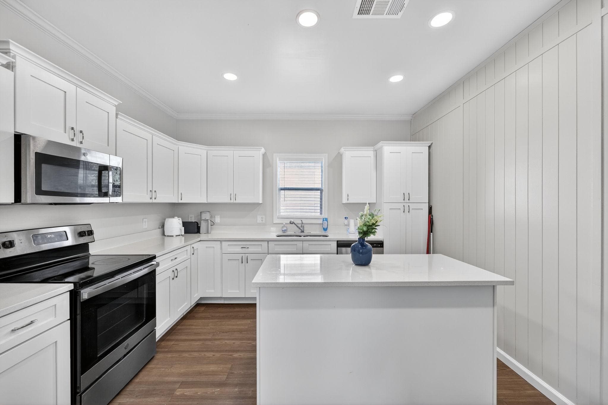 Step into this modern kitchen, where functionality meets style. The pristine white cabinetry and sleek black appliances create a striking contrast, while ample natural light fills the space. Perfect for cooking enthusiasts or casual dining, this kitchen invites you to make it your own!
