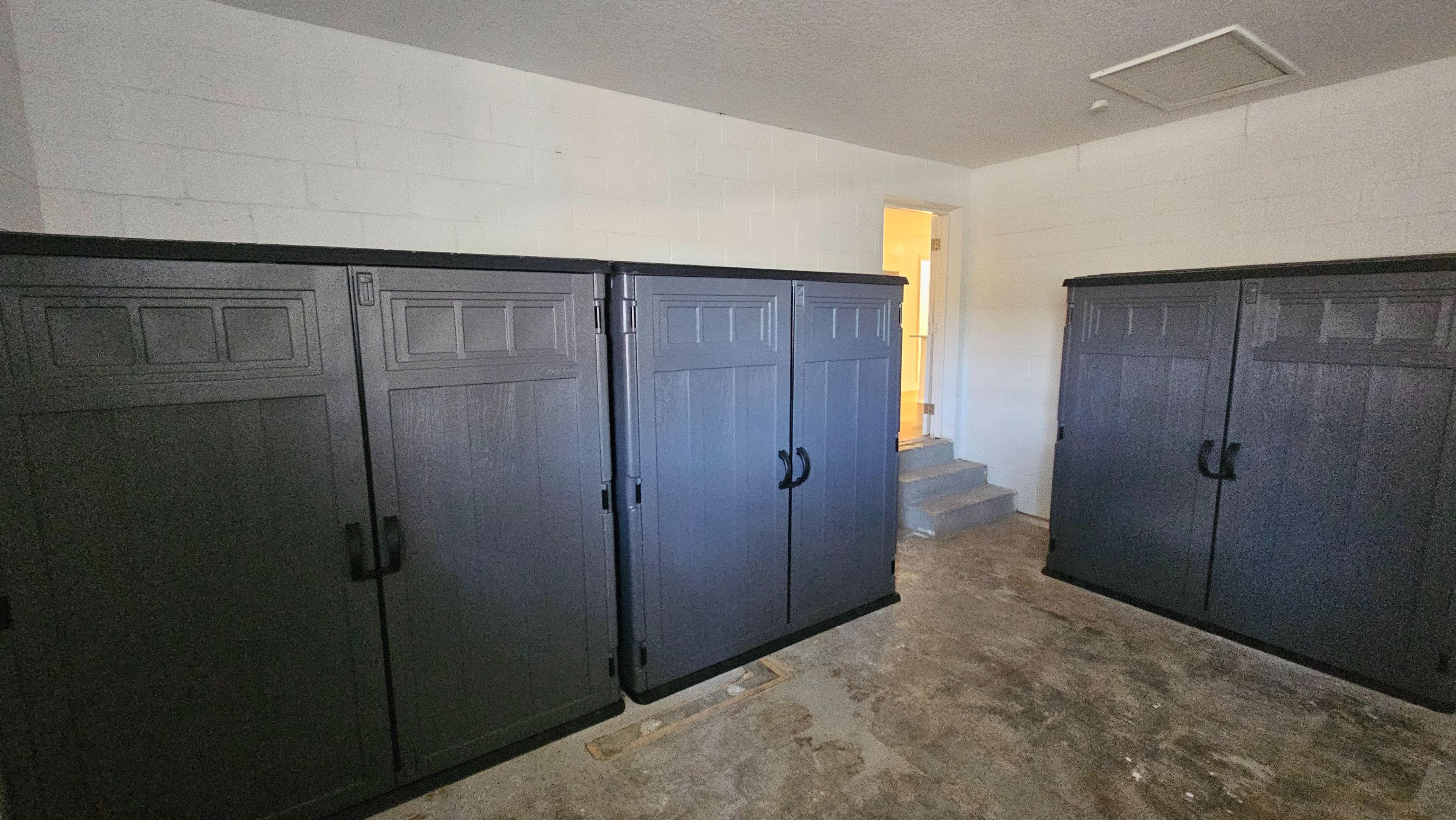 Functional storage area with multiple built-in cabinets, offering plenty of space to keep supplies and belongings organized. Photo is somewhat dim and the wide-angle perspective makes the room feel less inviting for a rental listing.