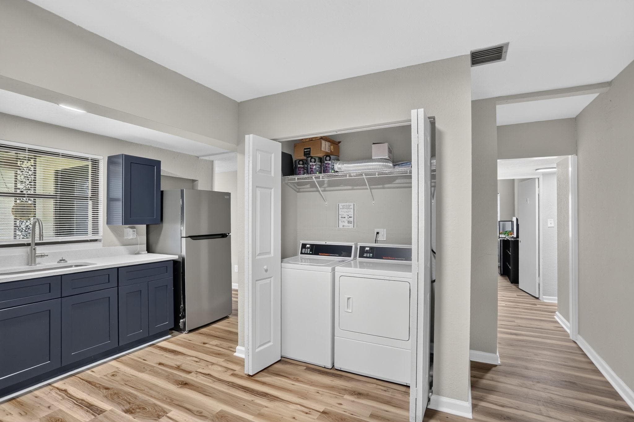 Convenient laundry nook with full-size washer/dryer plus nearby kitchen counters, sink, and fridge for easy daily living.