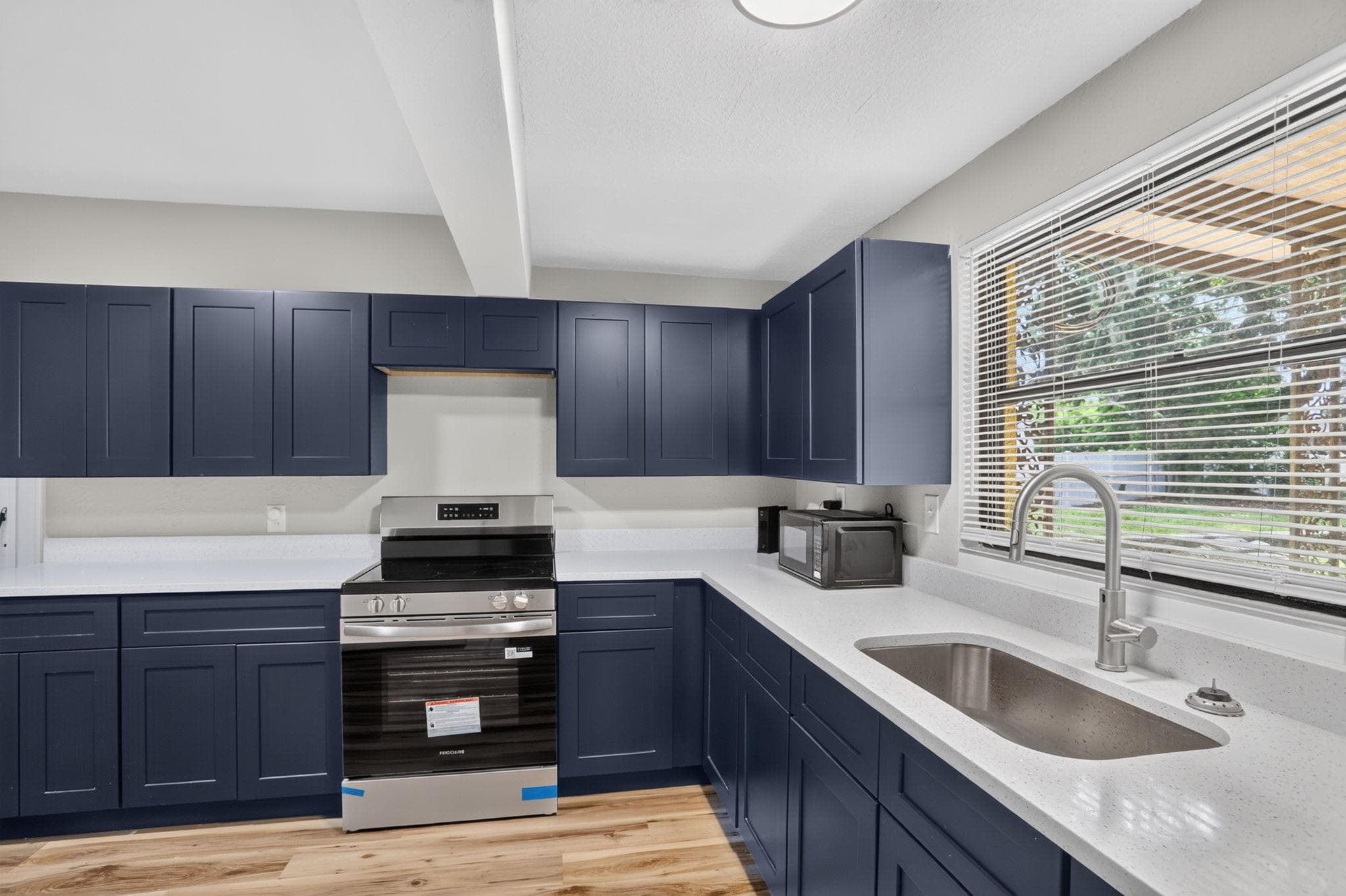 Updated kitchen with ample shaker cabinetry, generous counter space, stainless range, and a large window over the sink.