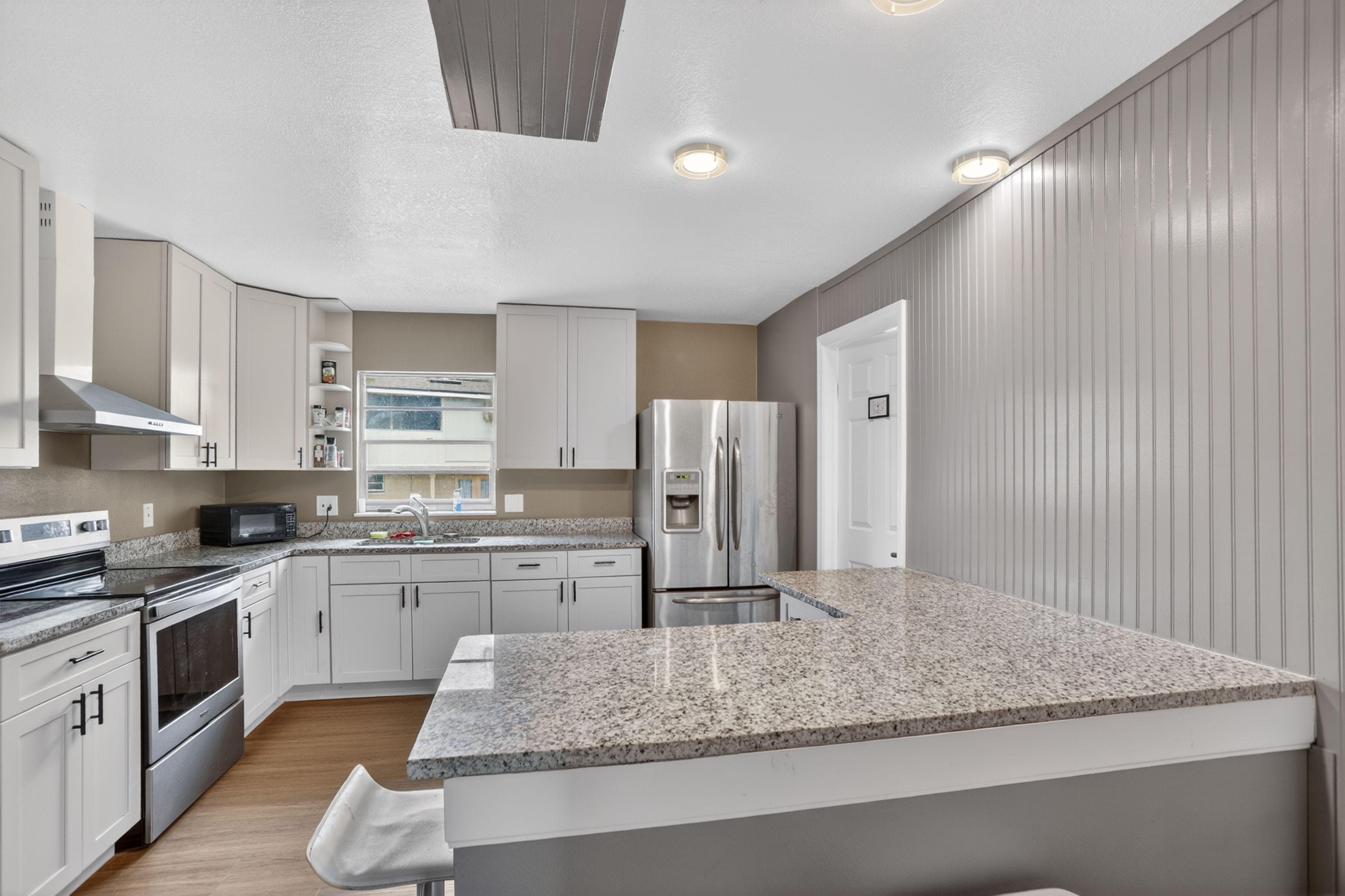 Updated kitchen with granite counters, ample cabinetry, and stainless appliances including a side-by-side refrigerator.