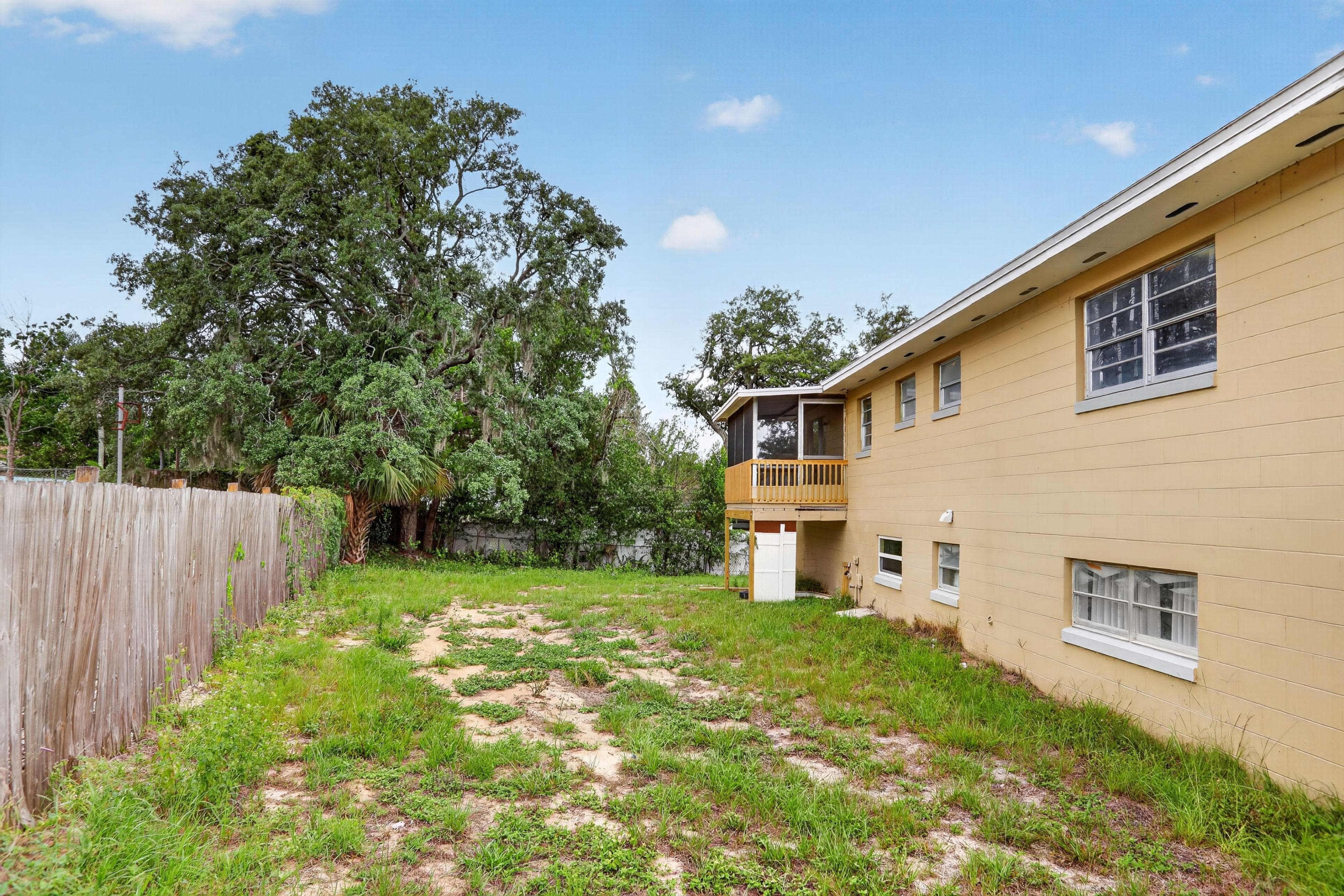 Fenced backyard with mature trees and a screened porch off the home, offering a private outdoor area for relaxing.