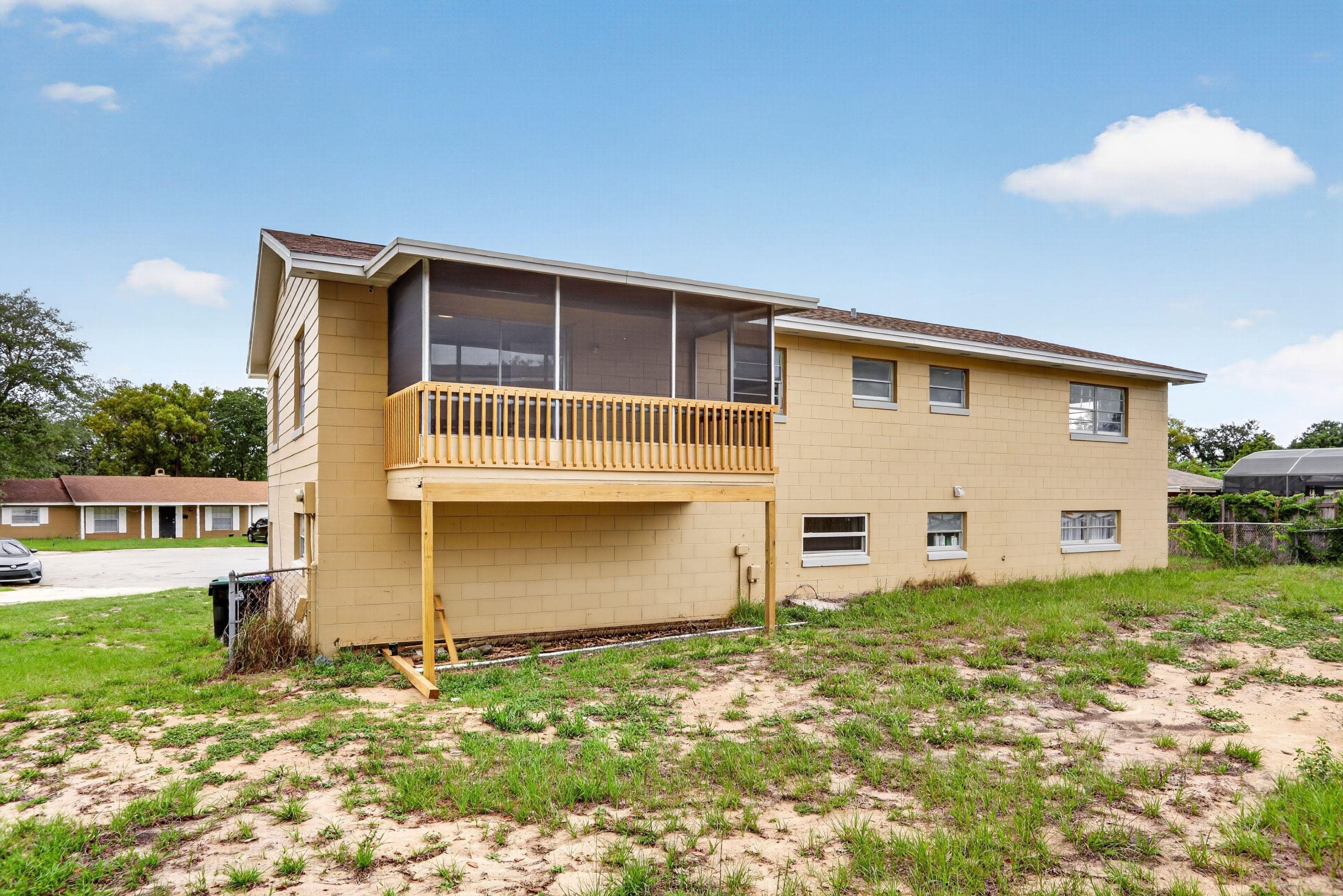 Two-story exterior with a screened upper porch and balcony railing, plus a spacious yard area for outdoor use.