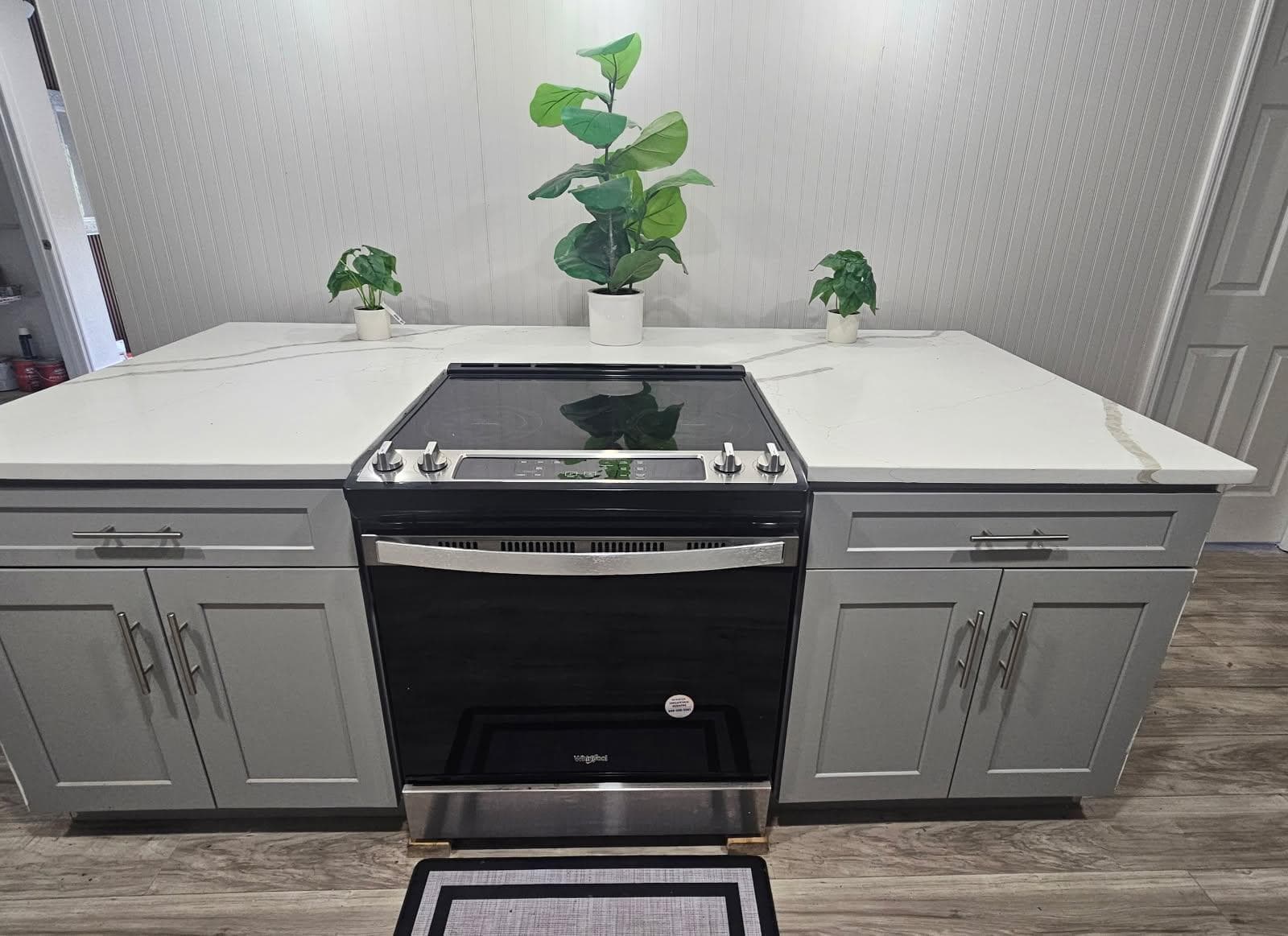 Kitchen features a sleek electric range with expansive quartz-look counters, ample lower cabinetry, and easy-care flooring.
