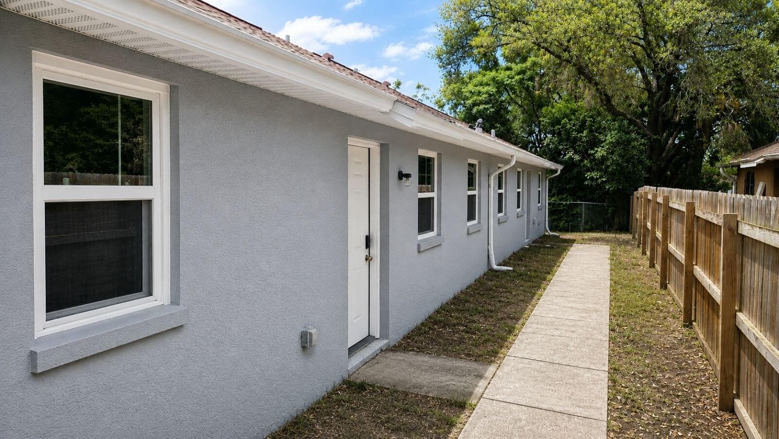 Private side yard with a paved walkway to a separate exterior entry, plus fenced space and mature shade trees.