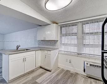 Eat-in kitchen area with ample cabinets, wide window with blinds, and durable flooring; includes a convenient in-room A/C uni