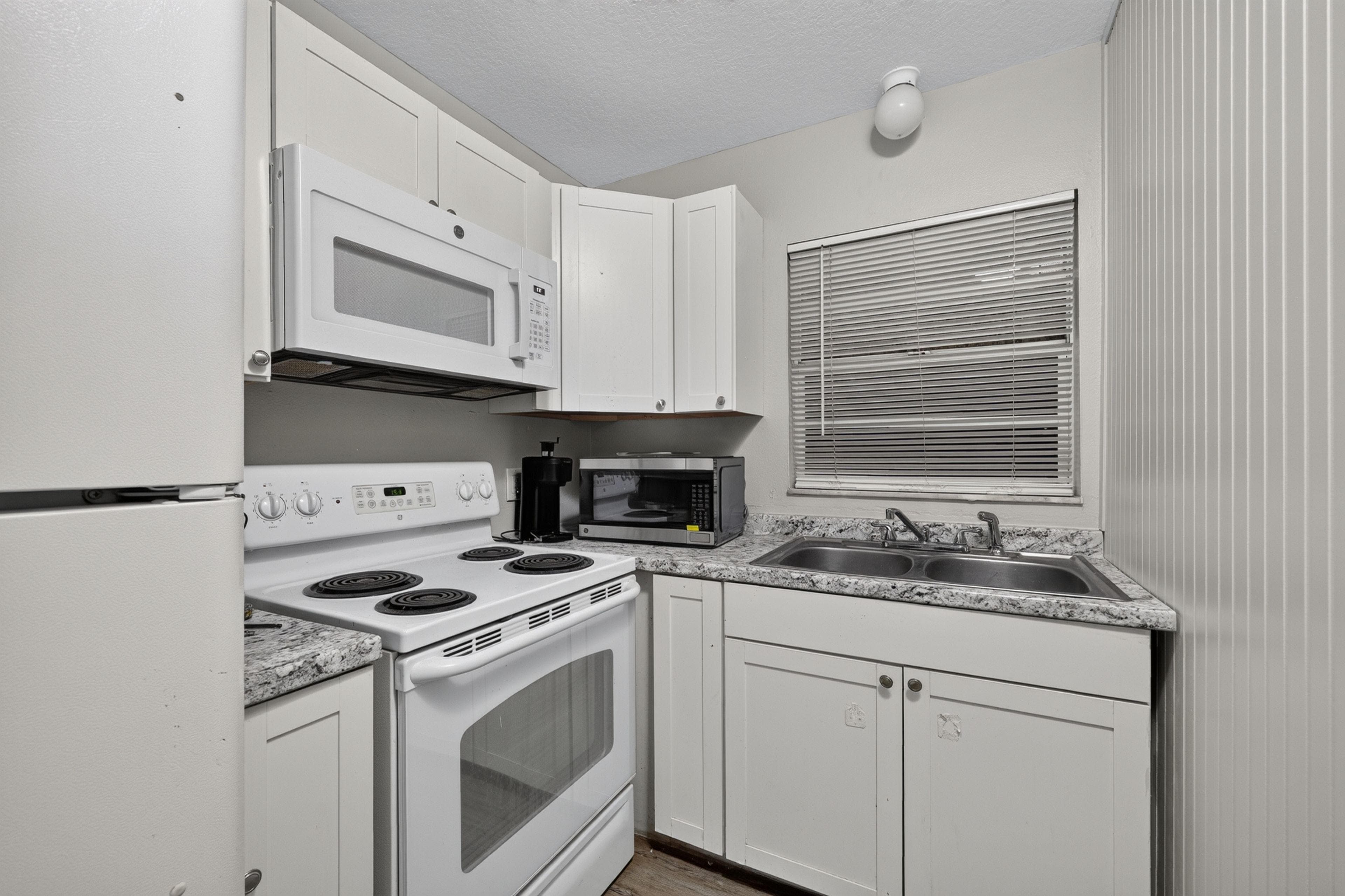 Efficient kitchen with ample cabinetry, laminate counters, double-basin sink, and a full appliance set for everyday cooking.